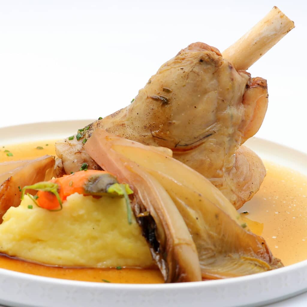 Jarret braisé gourmand, purée maison et chicorée fondante Jarret de veau braisé dressé sur une purée de pommes de terre crémeuse, accompagné de chicorée braisée et arrosé d'une sauce riche.